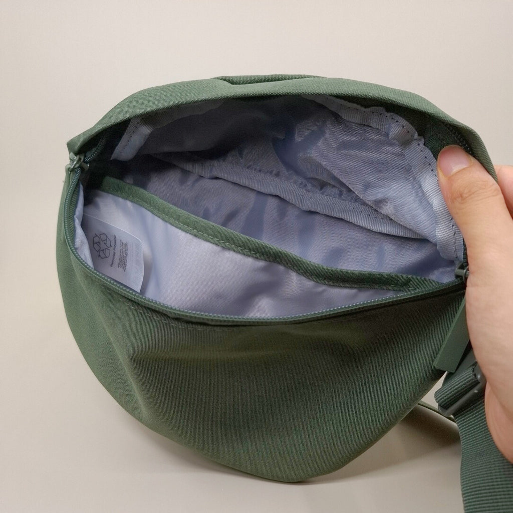 Olivgrüne Bauchtasche geöffnet. Die Tasch hat ein zusätzliches und gepolstertes Innenfach