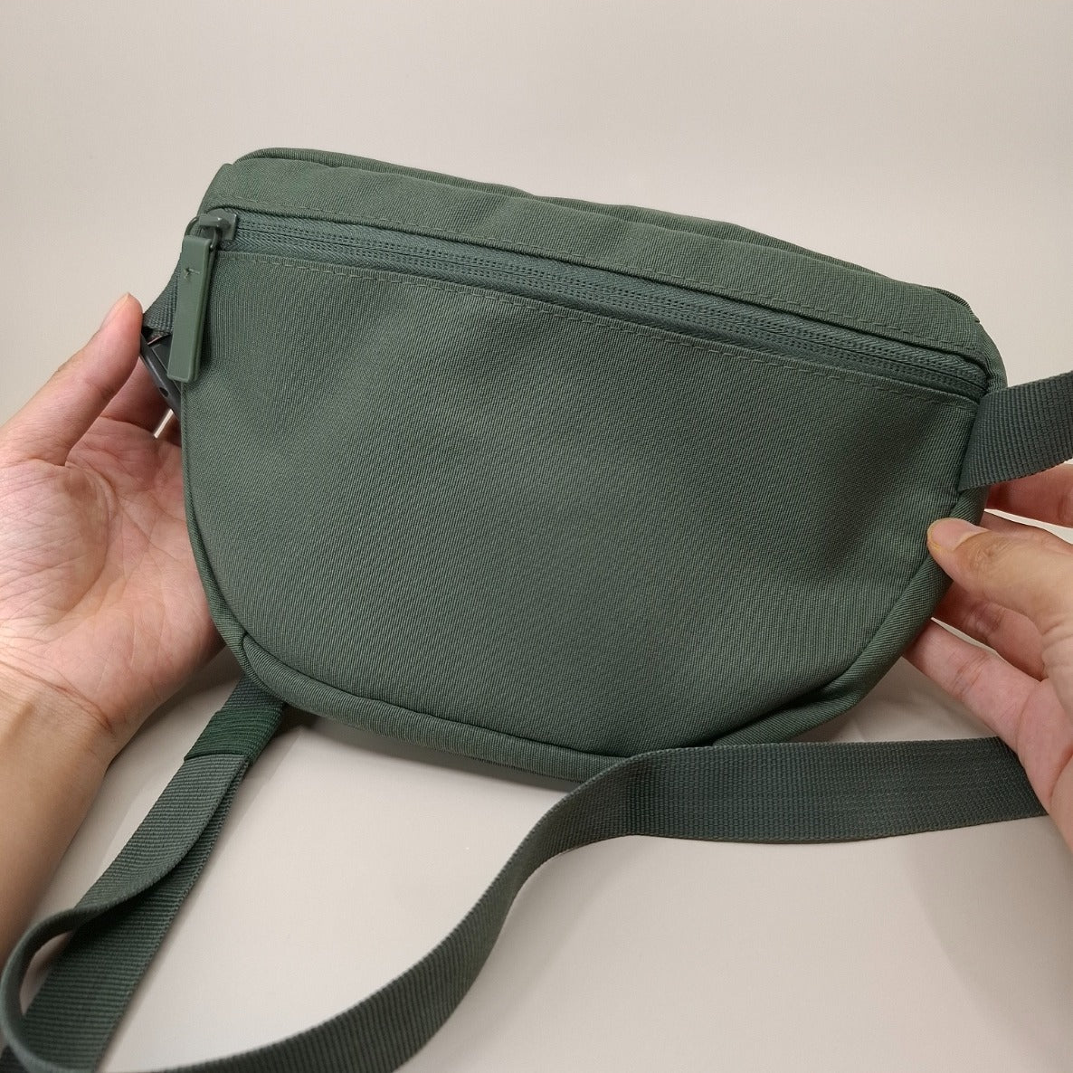 Olivgrüne Bauchtasche von hinten. Die Tasch hat dort eine Fach mit Reissverschluss