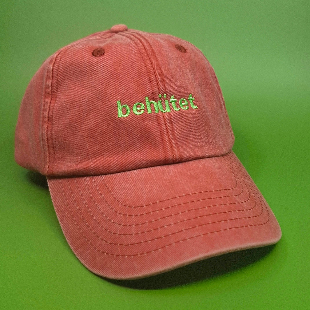 Orange Cap bestickt mit dem Text "behütet" in grün