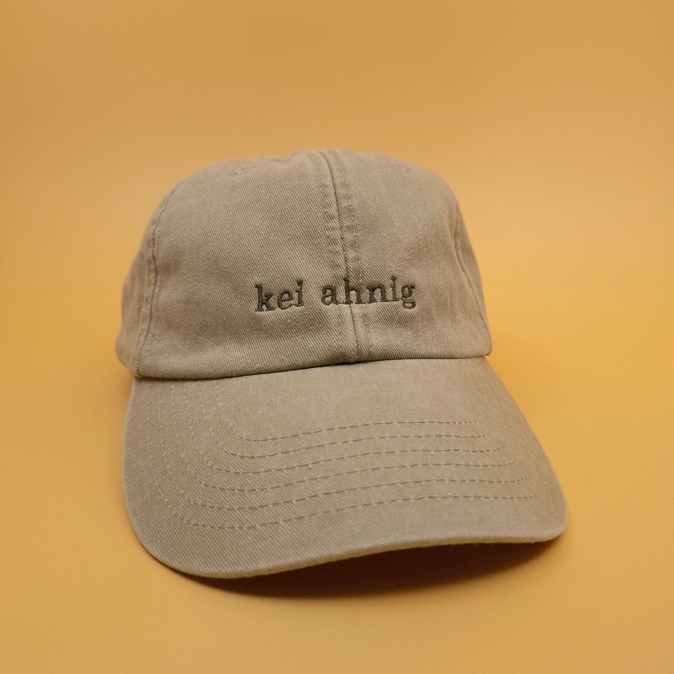 Beige Cap mit besticktem Text "kei ahnig" in dunkelbraun. 