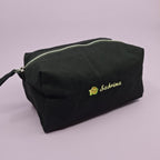 Schwarze Kosmetiktasche mit einem Sternfrucht-Icon und dem Namen "Sabrina" darauf gestickt.